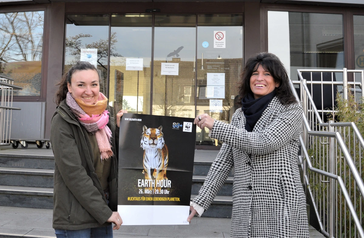 Klimaschutzmanagerin Ioanna Schmidt-Ioannidou und Bürgermeisterin Sabine Noll mit einem Plakat zur Earth Hour 2022