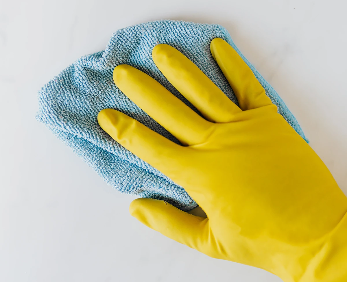Hand mit Gummihandschuh putzt...