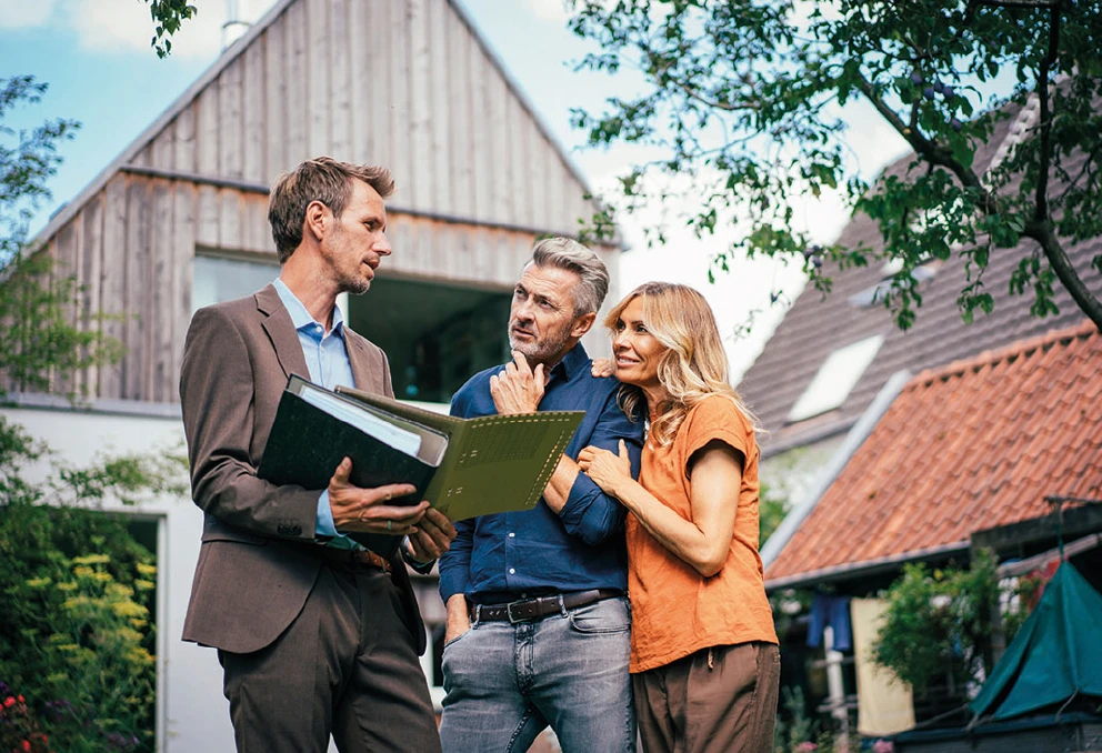 Immobilienberatung vor dem Haus, drei Personen